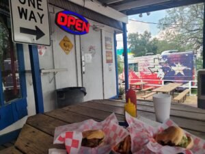 Table with burger and fries in front of local burger joint restaurant.